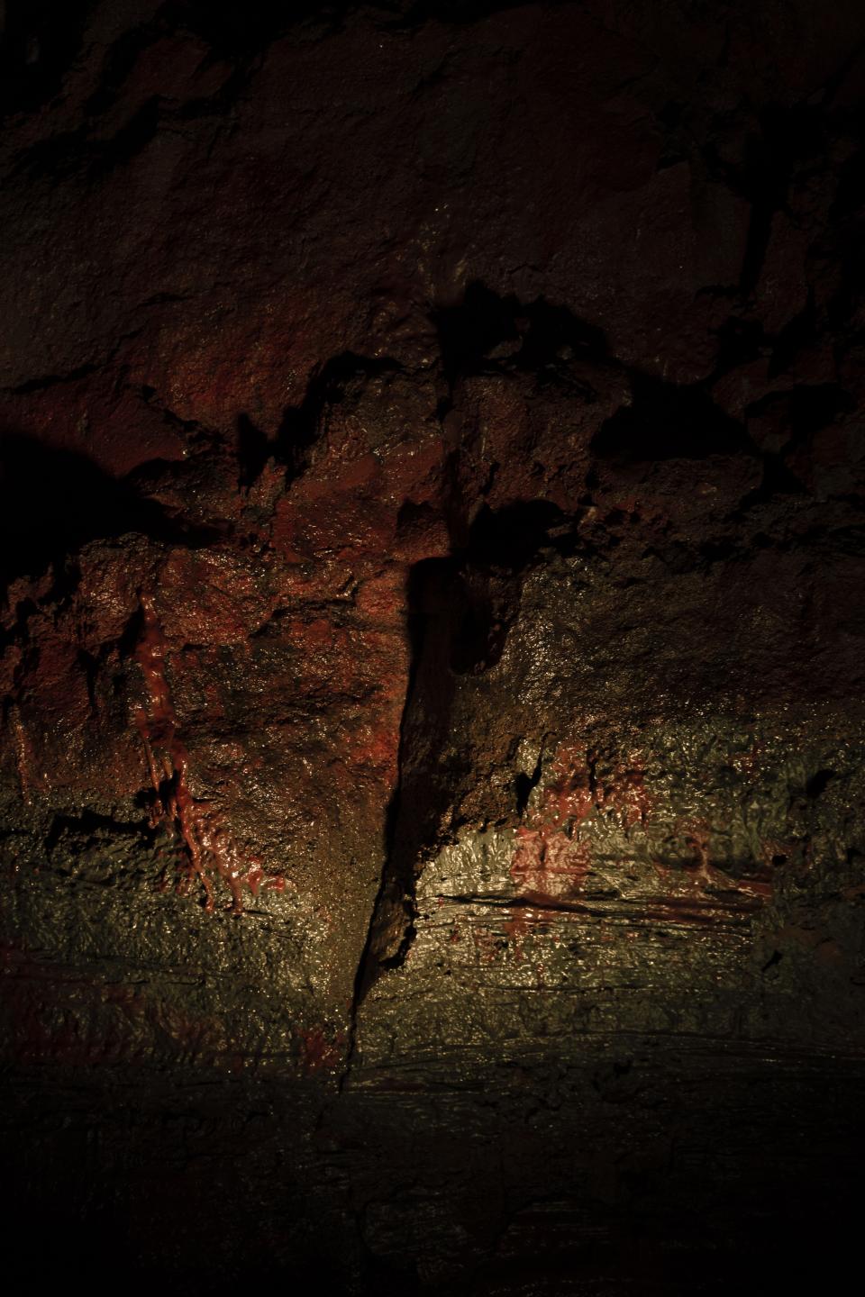 The rock is wet, iron-red.
Minerals run like slow blood along the walls.
Light slips in briefly, then vanishes.
Heat lingers in the dark.
The earth is open here.
Alive beneath its own surface.